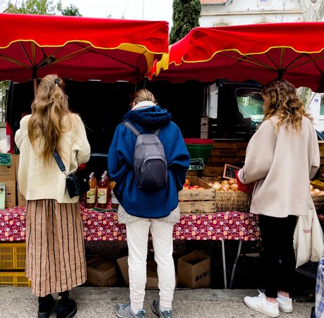 Trois femmes devant une étale au marché des arceaux.